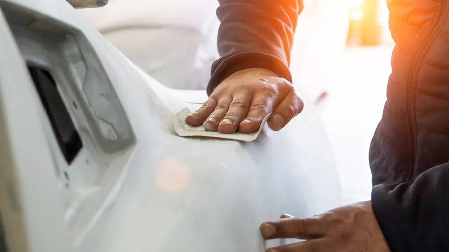 Man Cutting with Sandpaper on Car