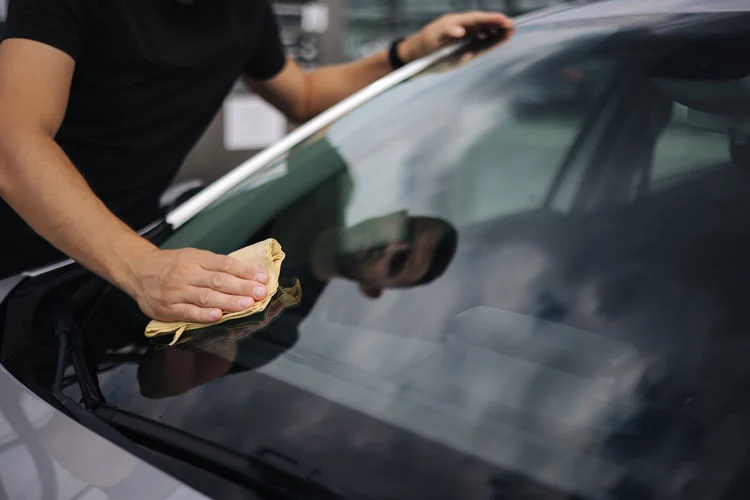 man removes scratches from the windshield