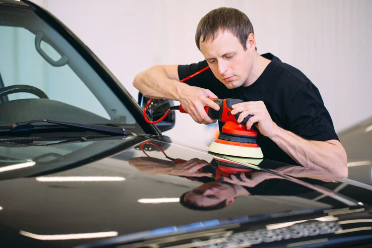 a man removing automobile scratch by polishing the car